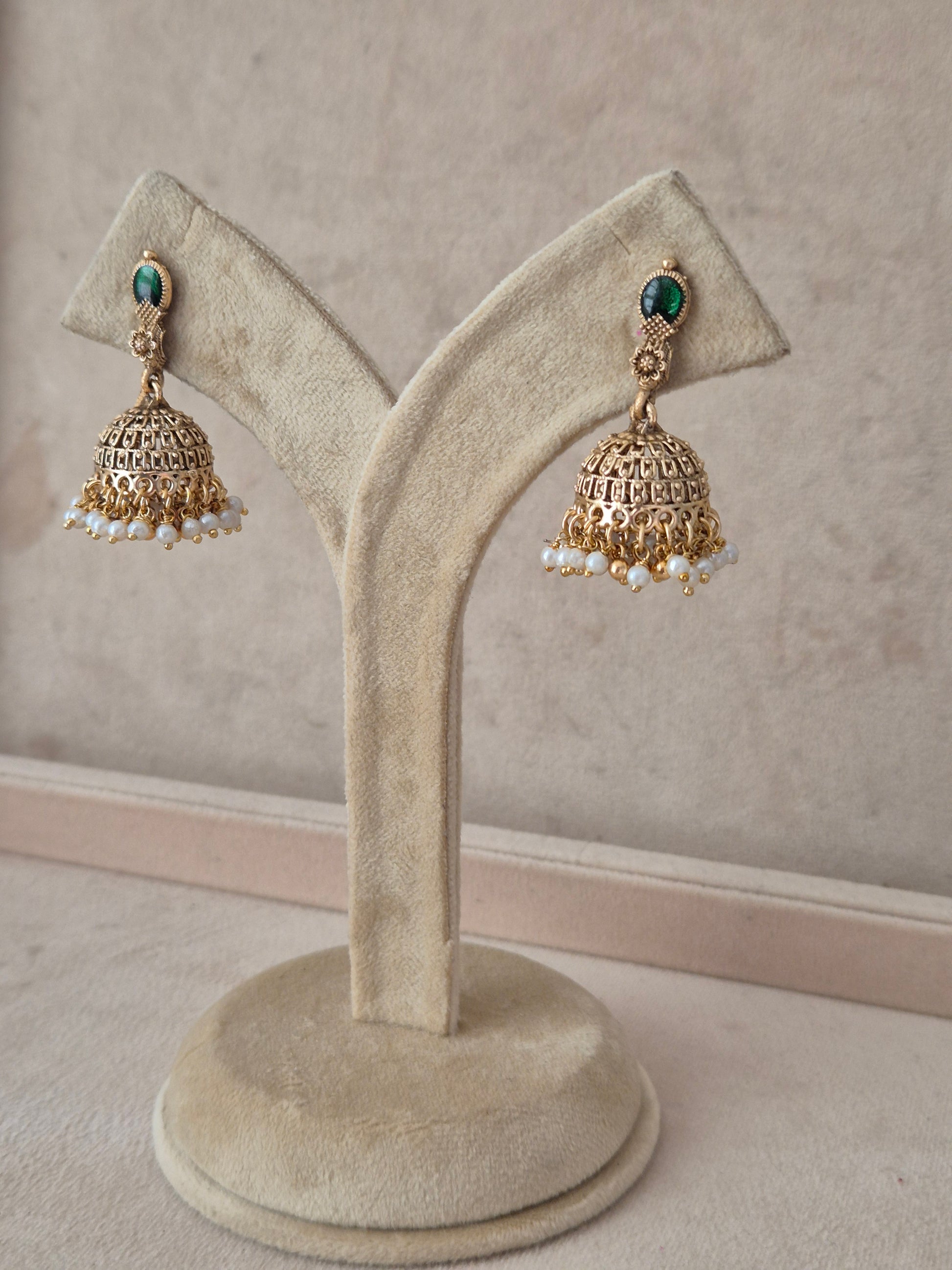 A pair of gold-toned Indian jhumka earrings with green stone accents and white pearl bead drops, by naitri.in