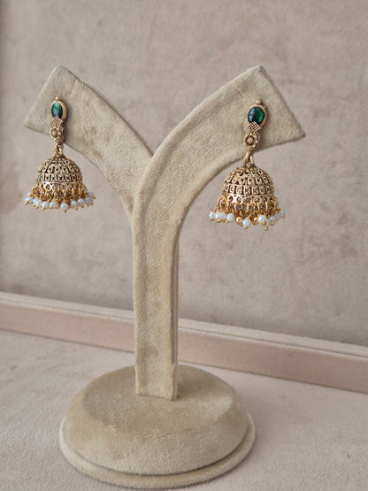 A pair of gold-toned Indian jhumka earrings with green stone accents and white pearl bead drops, by naitri.in