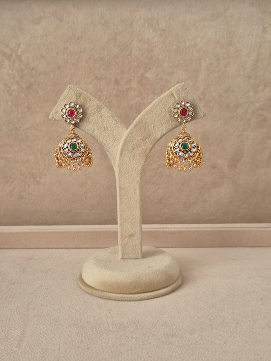Gold-plated traditional jhumka earrings featuring a circular floral stud studded with ruby-red and emerald-green stones, with tiny pearl drops by naitri.in