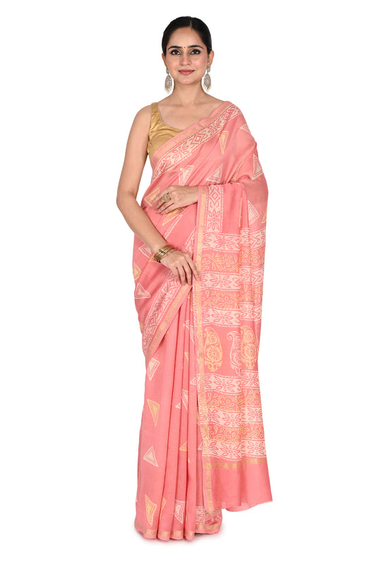 A woman wearing a peach-colored Ishi hand block printed cotton-silk saree with white geometric patterns and a gold border, styled with a sleeveless gold blouse by naitri.in