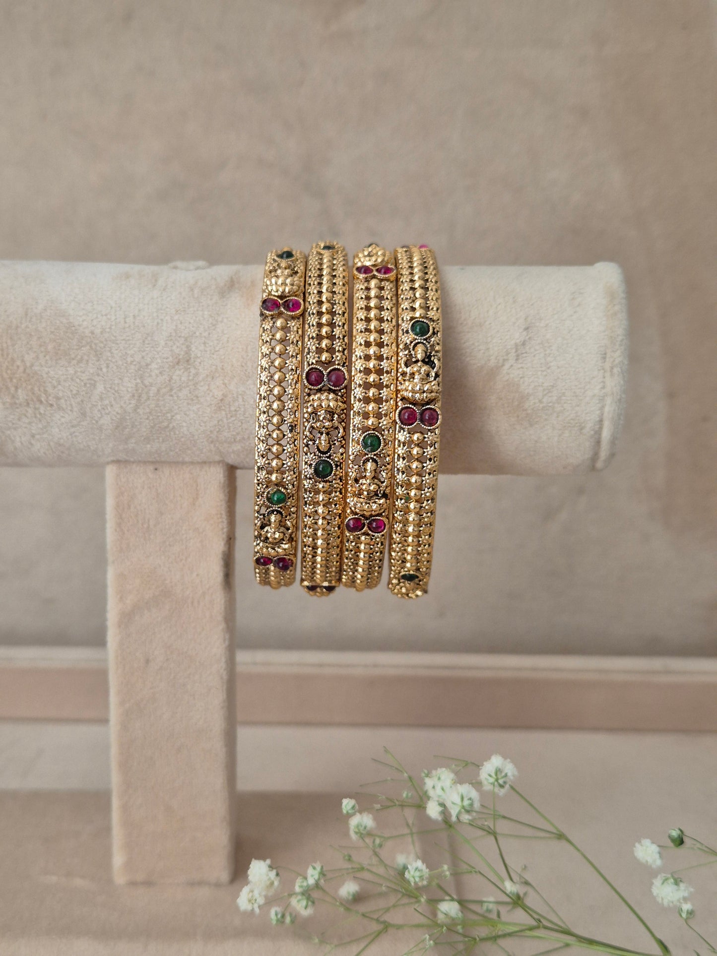 Three gold-plated beaded bangles with small green, red, and white stone accents, by naitri.in
