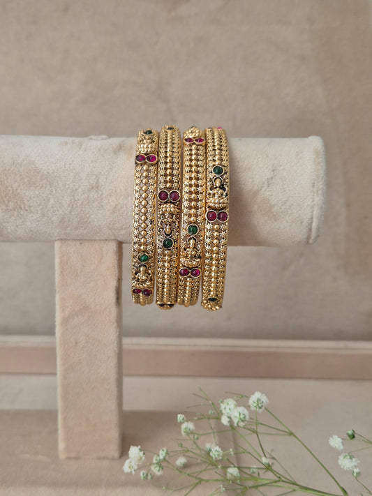 Three gold-plated beaded bangles with small green, red, and white stone accents, by naitri.in
