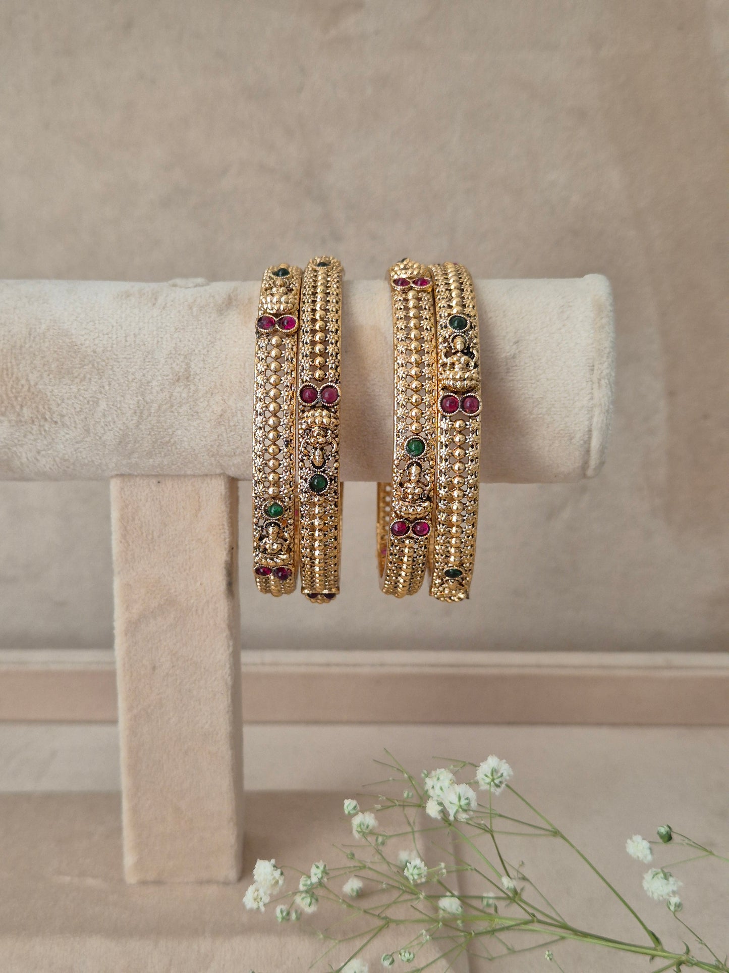 Traditional gold bangles with intricate textured bead patterns and colorful gemstone studded detailing, by naitri.in