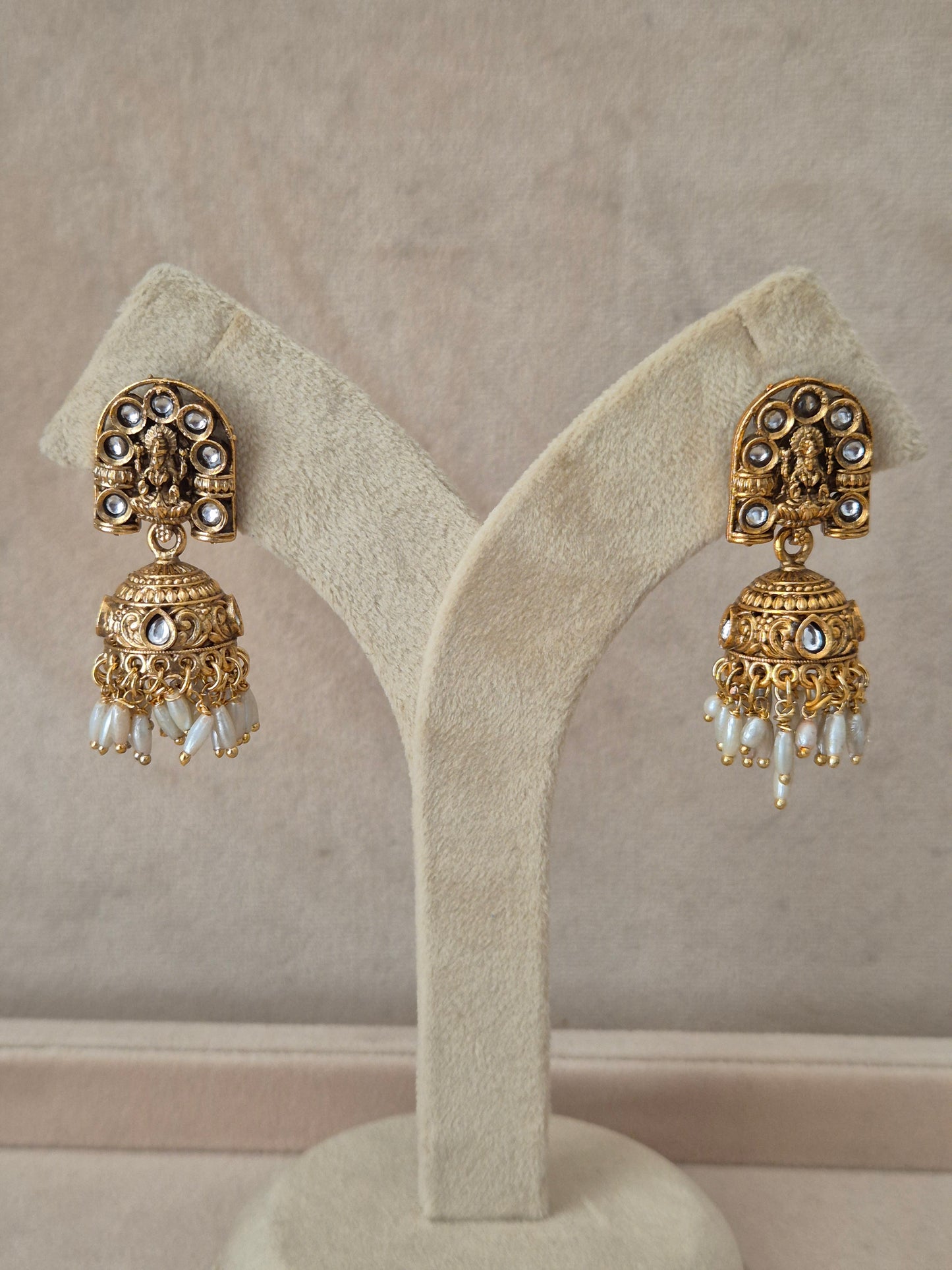 Traditional gold-plated Jhumka earrings with intricate engraving and white pearl dangling beads by naitri.in