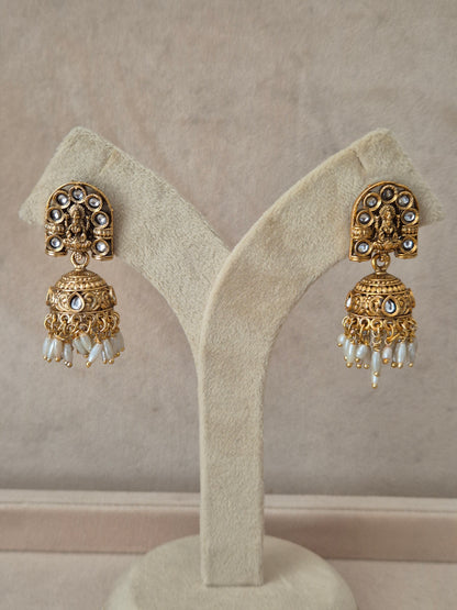Traditional gold-plated Jhumka earrings with intricate engraving and white pearl dangling beads by naitri.in