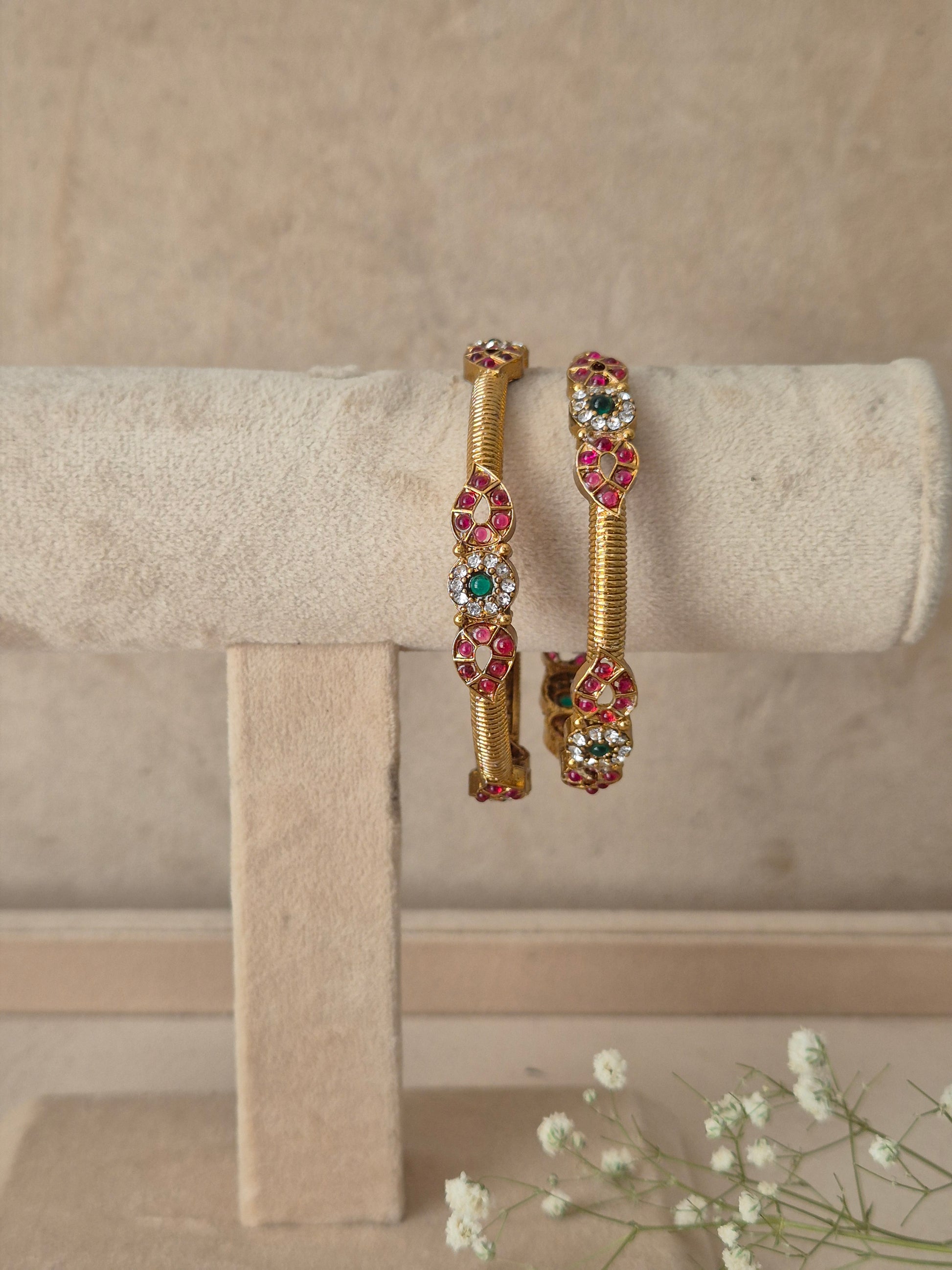 Two gold-plated bangles with red and green stone embellishments, by naitri.in