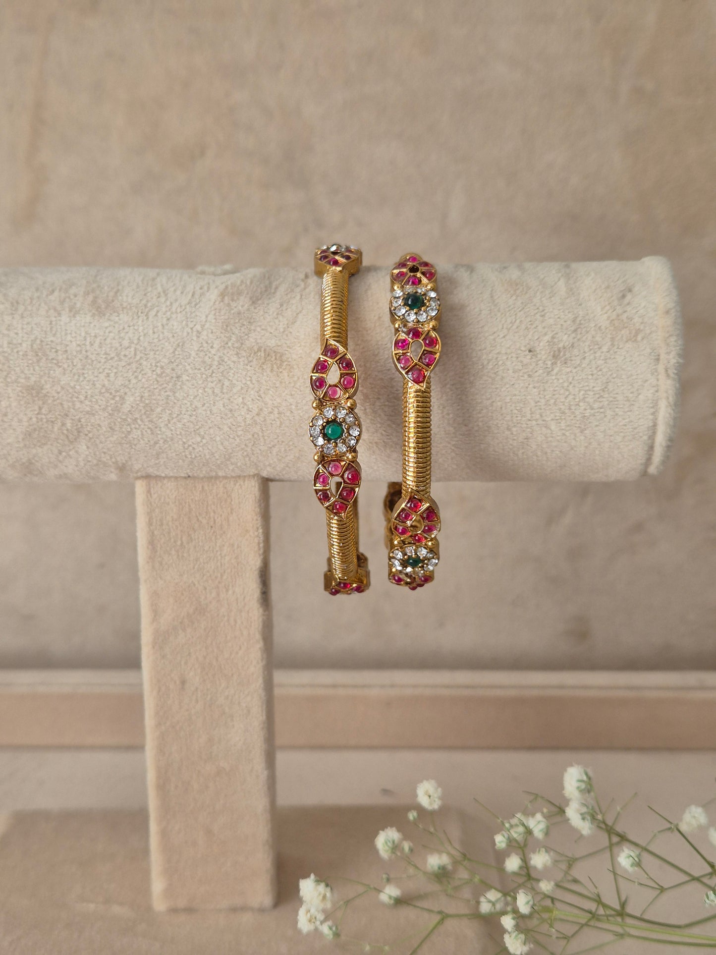 Two gold-plated bangle with circular pink and green gemstone clusters, by naitri.in