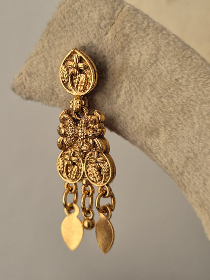 An ornate gold-toned dangle earring with intricate filigree detailing and three hanging leaf-shaped charms, by naitri.in