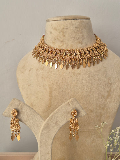 Gold-toned traditional jewelry set,  including a choker necklace with dangling leaf-shaped charms and matching drop earrings, by naitri.in