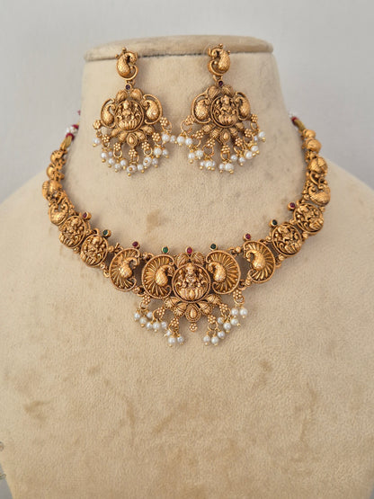 Gold-toned traditional Indian jewelry set featuring a choker necklace and matching earrings with intricate filigree work, floral motifs, and pearl bead clusters, by naitri.in