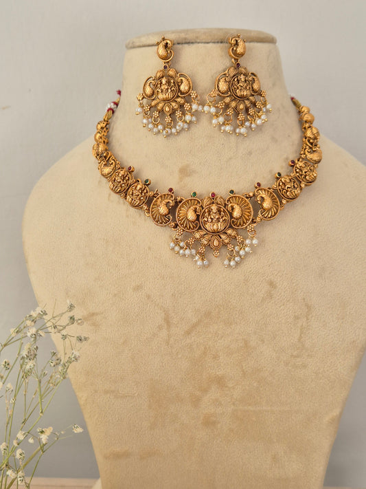 Gold-plated antique Indian choker necklace and matching large drop earrings set necklace features traditional coin-shaped medallions with intricate filigree motifs, an engraving of a goddess figure, and a delicate fringe of hanging white faux pearls by naitri.in
