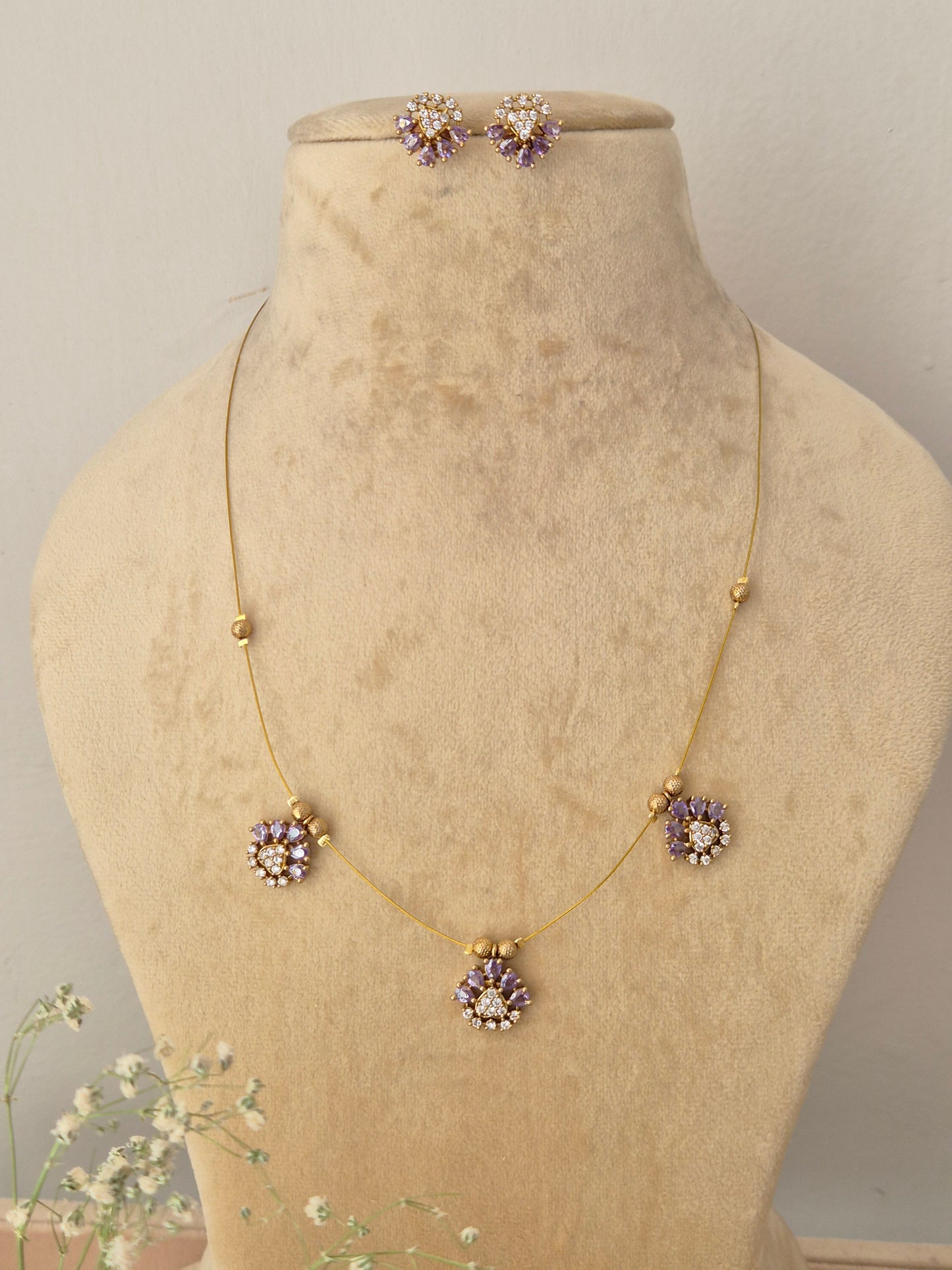 Delicate gold invisible chain necklace with lavender floral pendants and matching stud earrings, by naitri.in