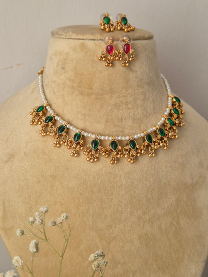 Gold-polished delicate pearl choker with green kemp stone embellishments and matching versatile stud earrings from the Golden Ethnic Jewellery line by naitri.in