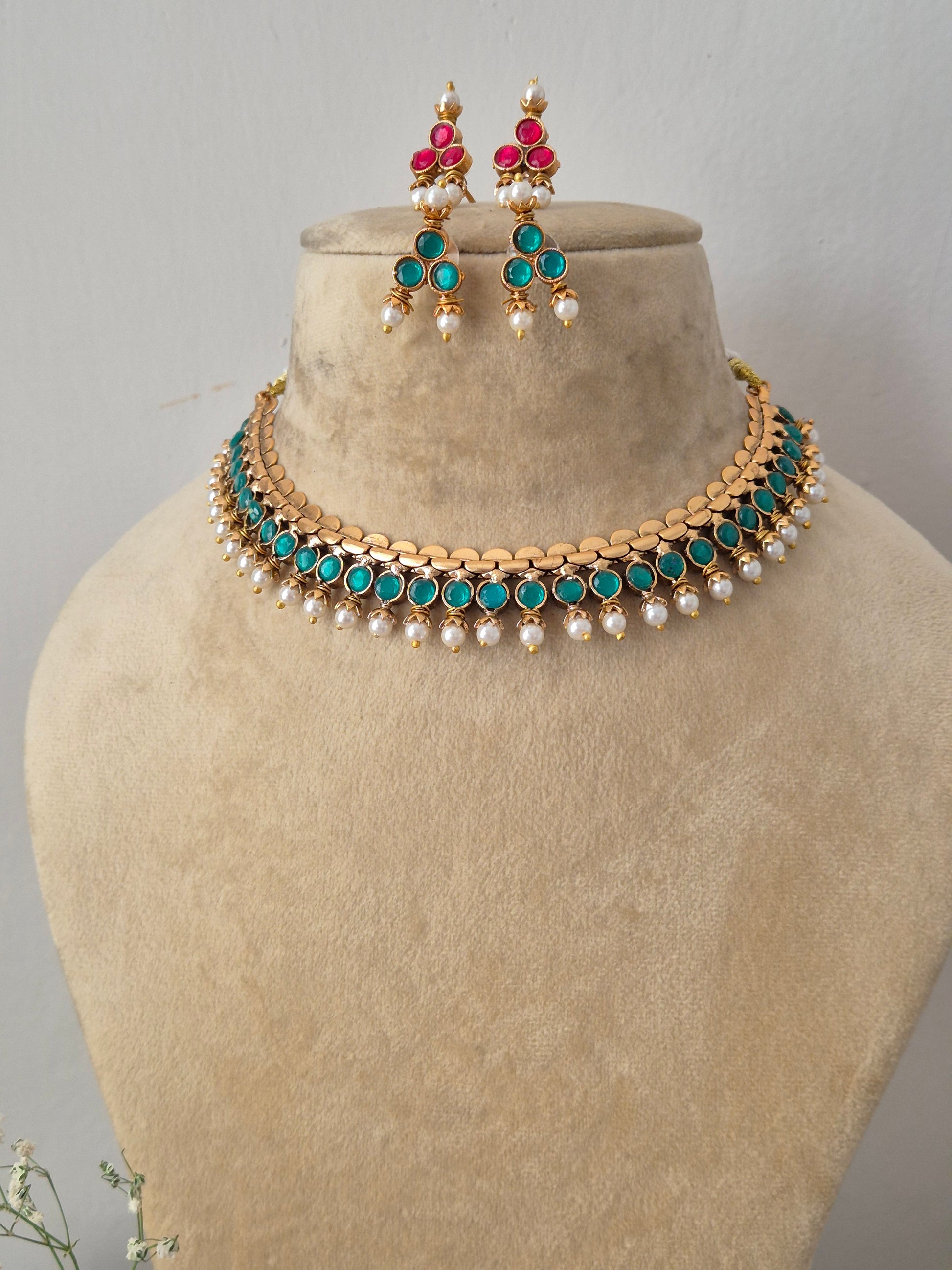 Handcrafted dual-sided statement gold choker set adorned with ruby-pink gemstones and tiny pearl drops by naitri.in
