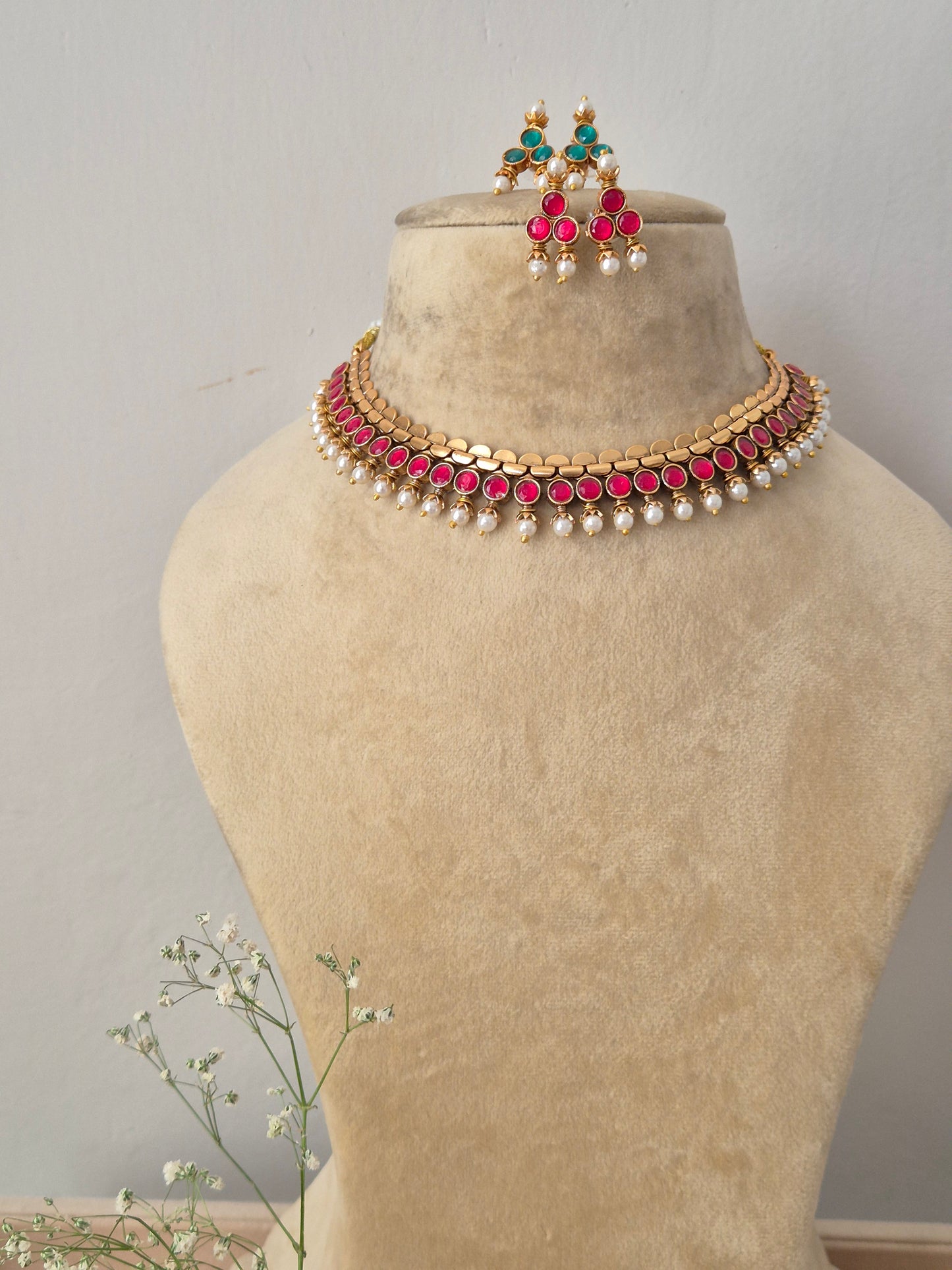 Gold-toned reversible choker necklace featuring pink gemstone accents and hanging pearls, with matching earrings by naitri.in
