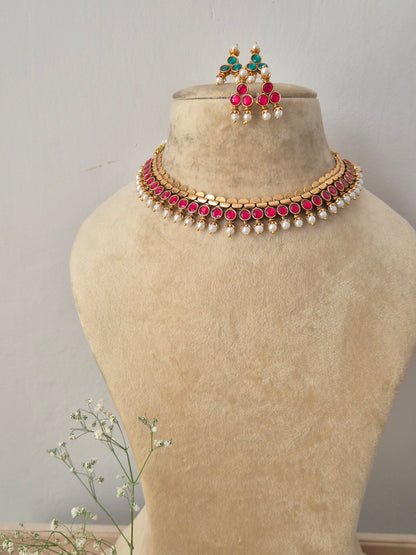 Gold-toned reversible choker necklace featuring pink gemstone accents and hanging pearls, with matching earrings by naitri.in