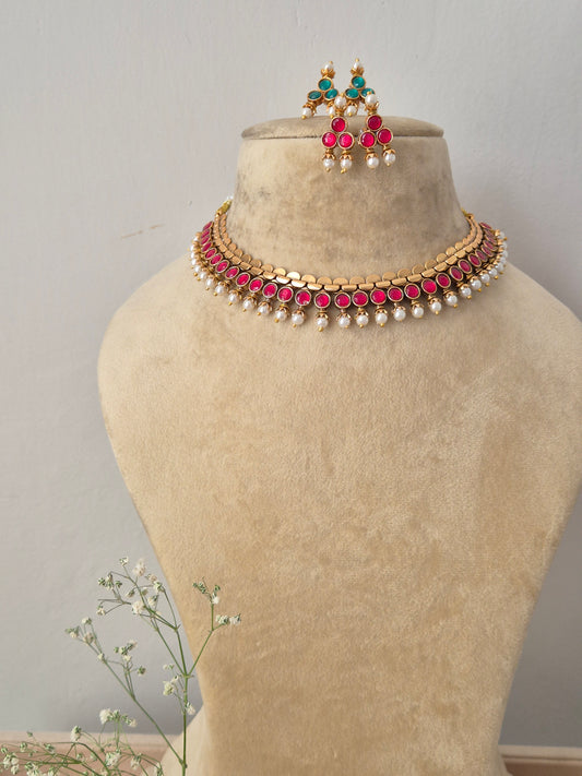 Gold-toned reversible choker necklace featuring pink gemstone accents and hanging pearls, with matching earrings by naitri.in