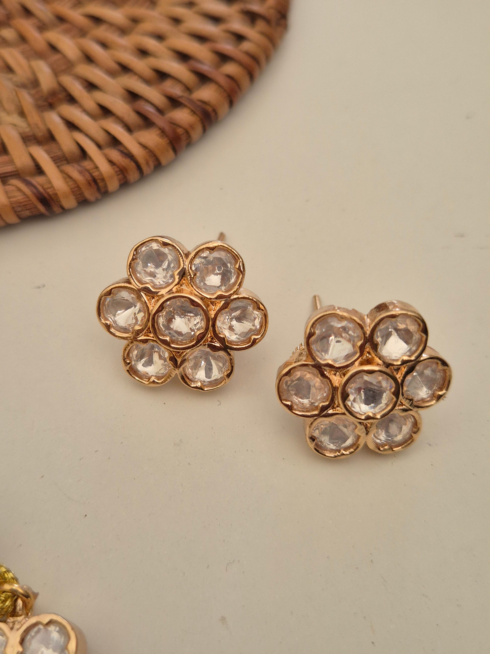 A rose gold-toned earring with oval-shaped clear crystals making floral-patterned stud by naitri.in