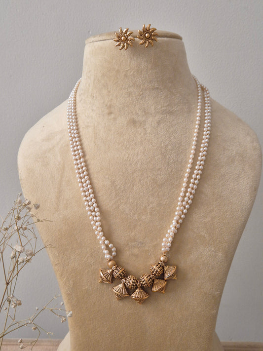 et featuring a multi-strand white pearl necklace with five gold-toned textured jhumka pendants and matching floral stud earrings by naitri.in
