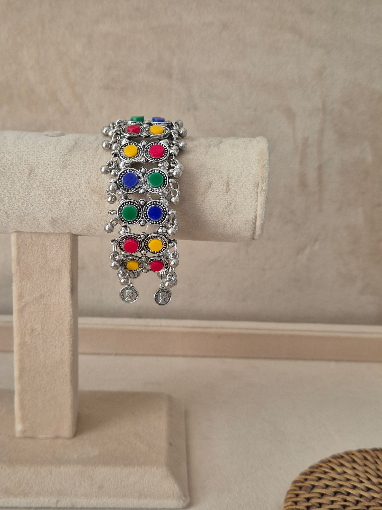 Oxidized silver Jharna bangle bracelet featuring vertical rows of vibrant multi-colored enamel circular charms in red, green, blue, and yellow, detailed with filigree borders and dangling silver ghungroo beads by naitri.in