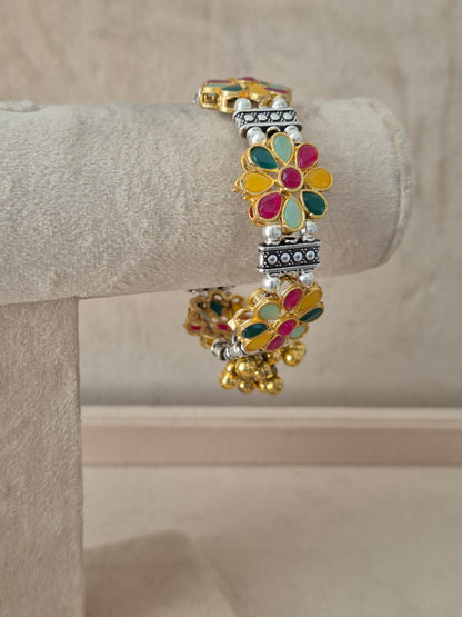 Statement gold and silver-plated festive Kada bangle featuring intricate rows of oxidized beads, colorful hand-painted floral panels, and a cluster of hanging gold beads, By naitri.in