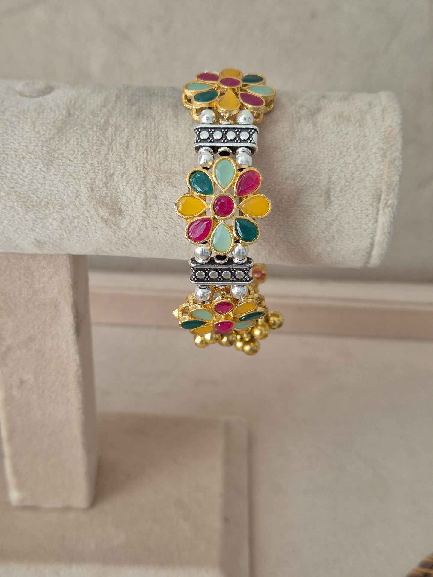 Jigesha bangle with multi-colored enamel flowers and dangling gold ghungroo charms Elegant dual-tone bohemian cuff bracelet with traditional Indian festive detail by naitri.in