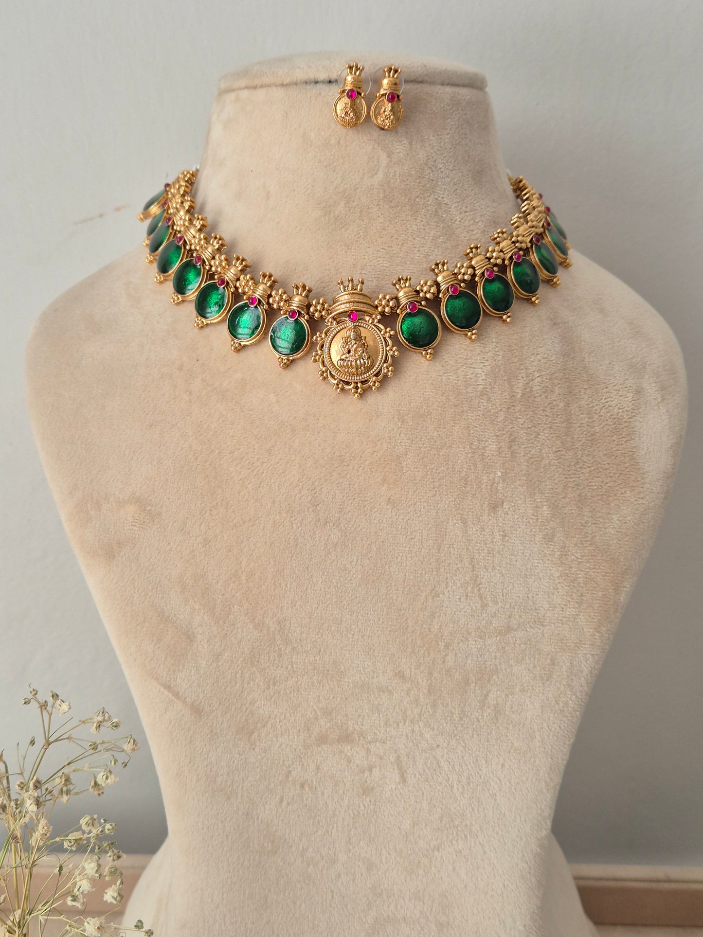 Gold-plated traditional Indian jewelry set featuring a necklace and matching earrings with green stones and small red accent stones,  by naitri.in