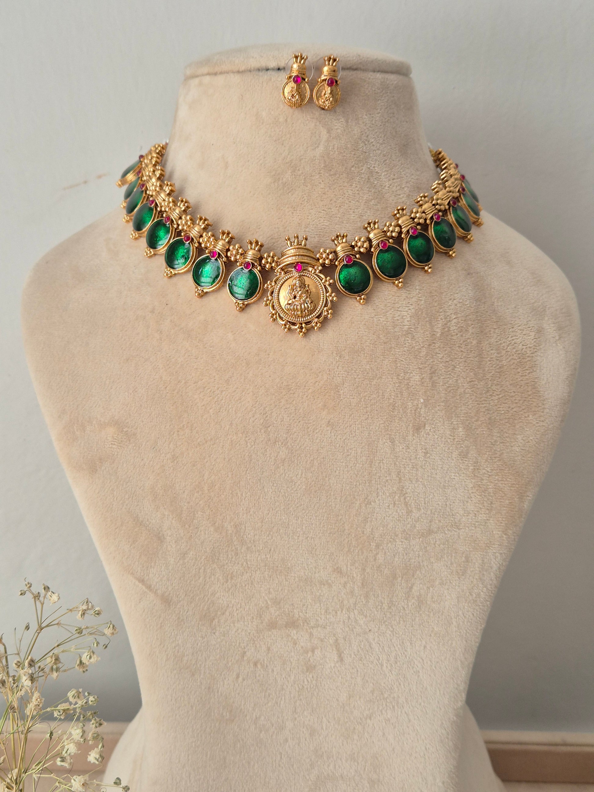 Gold-plated traditional Indian jewelry set featuring a necklace and matching earrings with green stones and small red accent stones,  by naitri.in