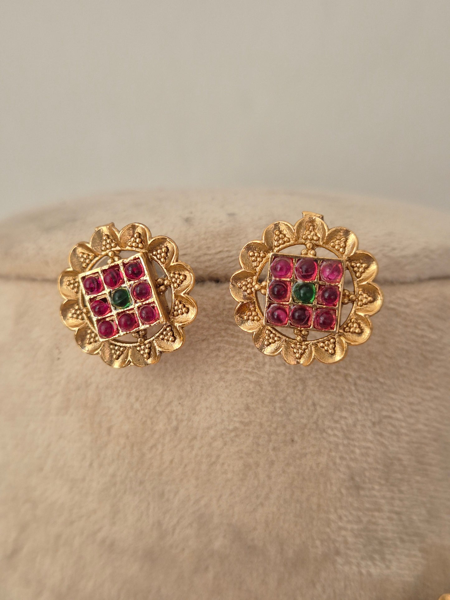 Traditional imitation stud earrings crafted with brass alloy and red-green stone studded round links by naitri.in