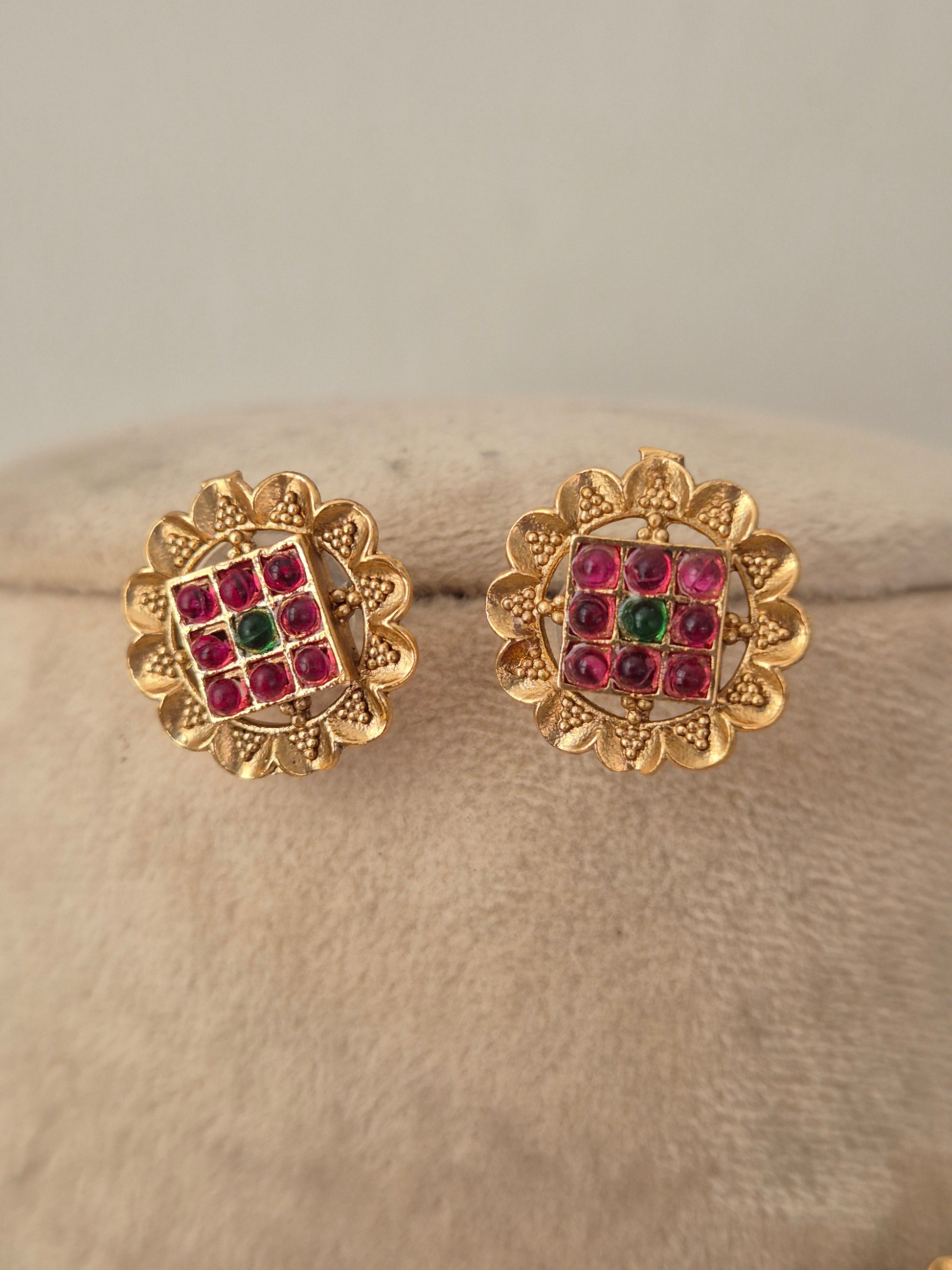 Traditional imitation stud earrings crafted with brass alloy and red-green stone studded round links by naitri.in