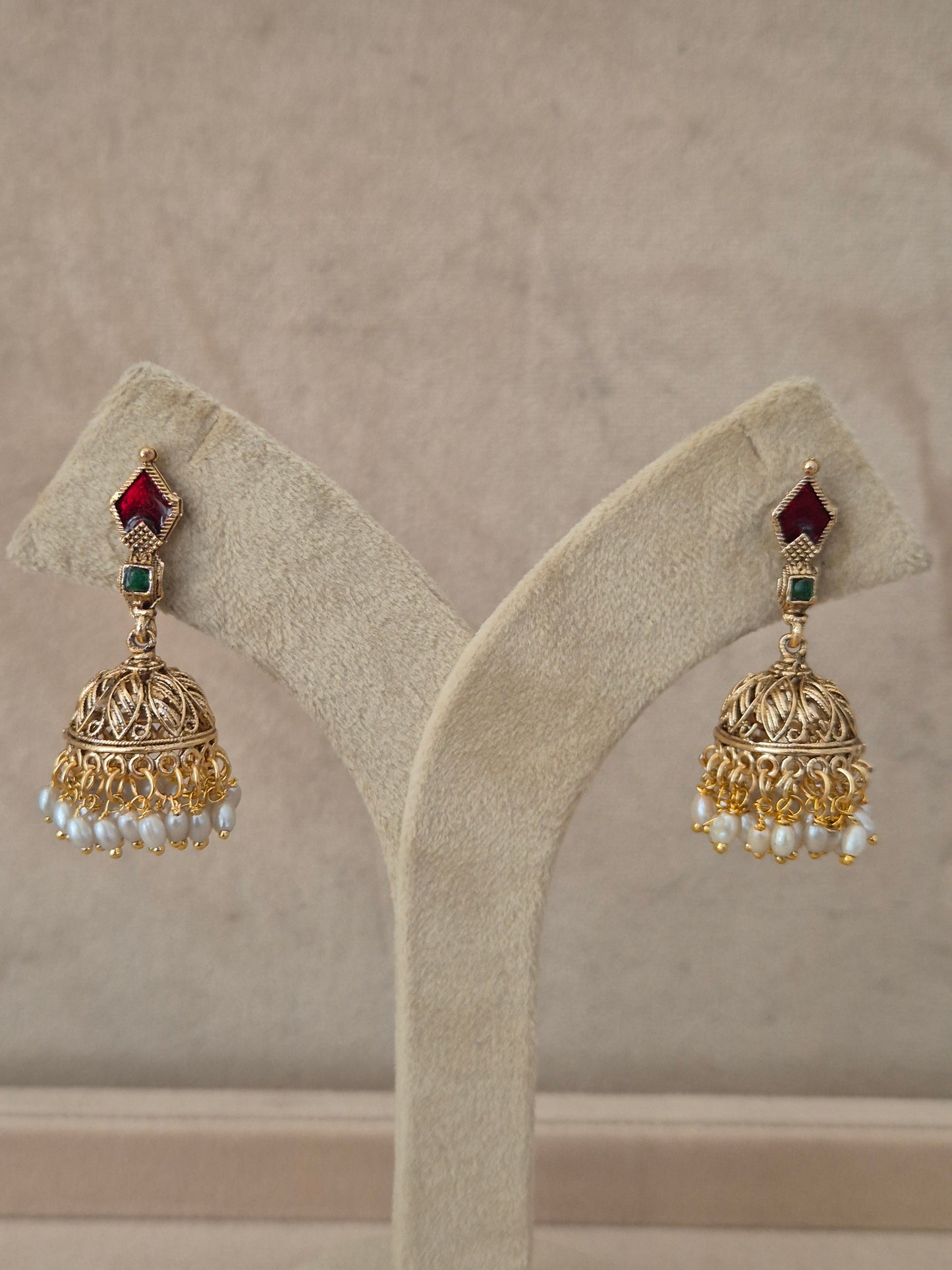 Traditional gold-plated Kalindi Jhumka earrings with red and green stones and small white dangling pearls by naitri.in