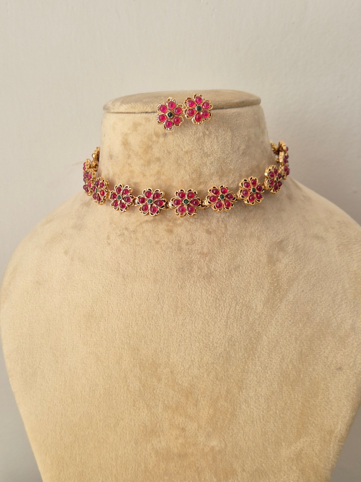 Handcrafted antique gold statement jewelry set featuring delicate pink and green floral stone embellishments, ideal for festive and traditional styling by naitri.in