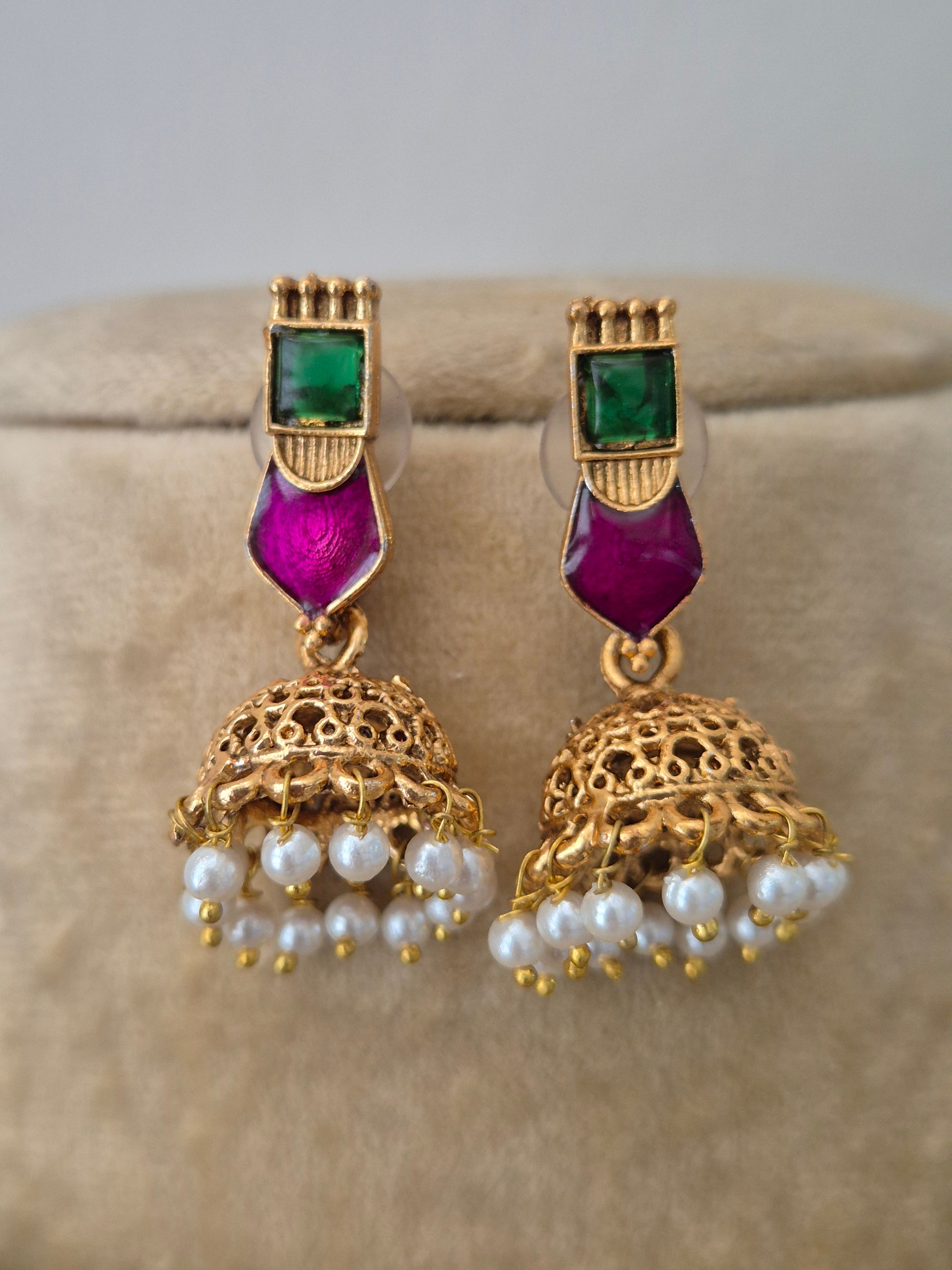 a golden brass alloy earring embedded with vibrant green and pink stones jhumka earrings featuring white pearl drops by naitri.in