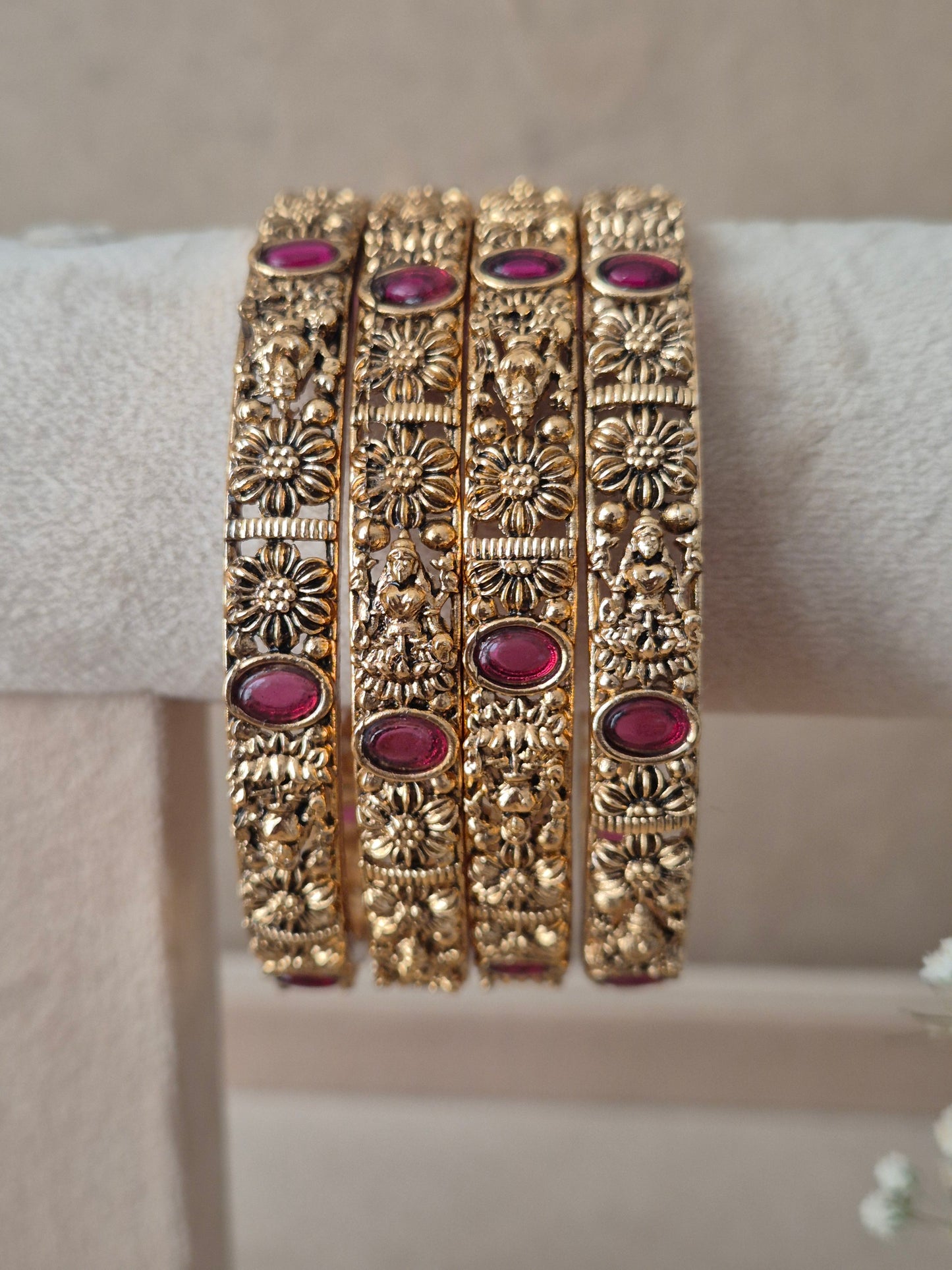 Set of four traditional gold-toned bangles with detailed engraving and red stones by naitri.in