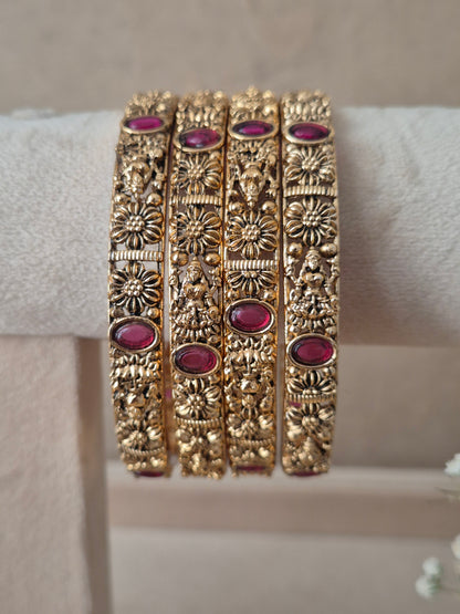 Set of four traditional gold-toned bangles with detailed engraving and red stones by naitri.in
