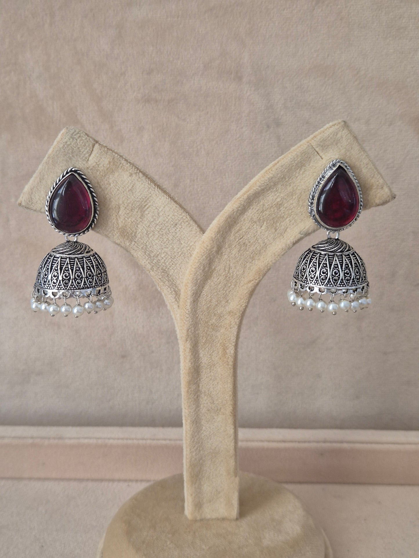 Naitri premium Kasturi oxidized silver jhumka earrings with purple stones from the Silver Jewellery collection. Handcrafted silver oxidized dangle jhumka earrings with dark purple gemstones and small pearl accents by naitri.in