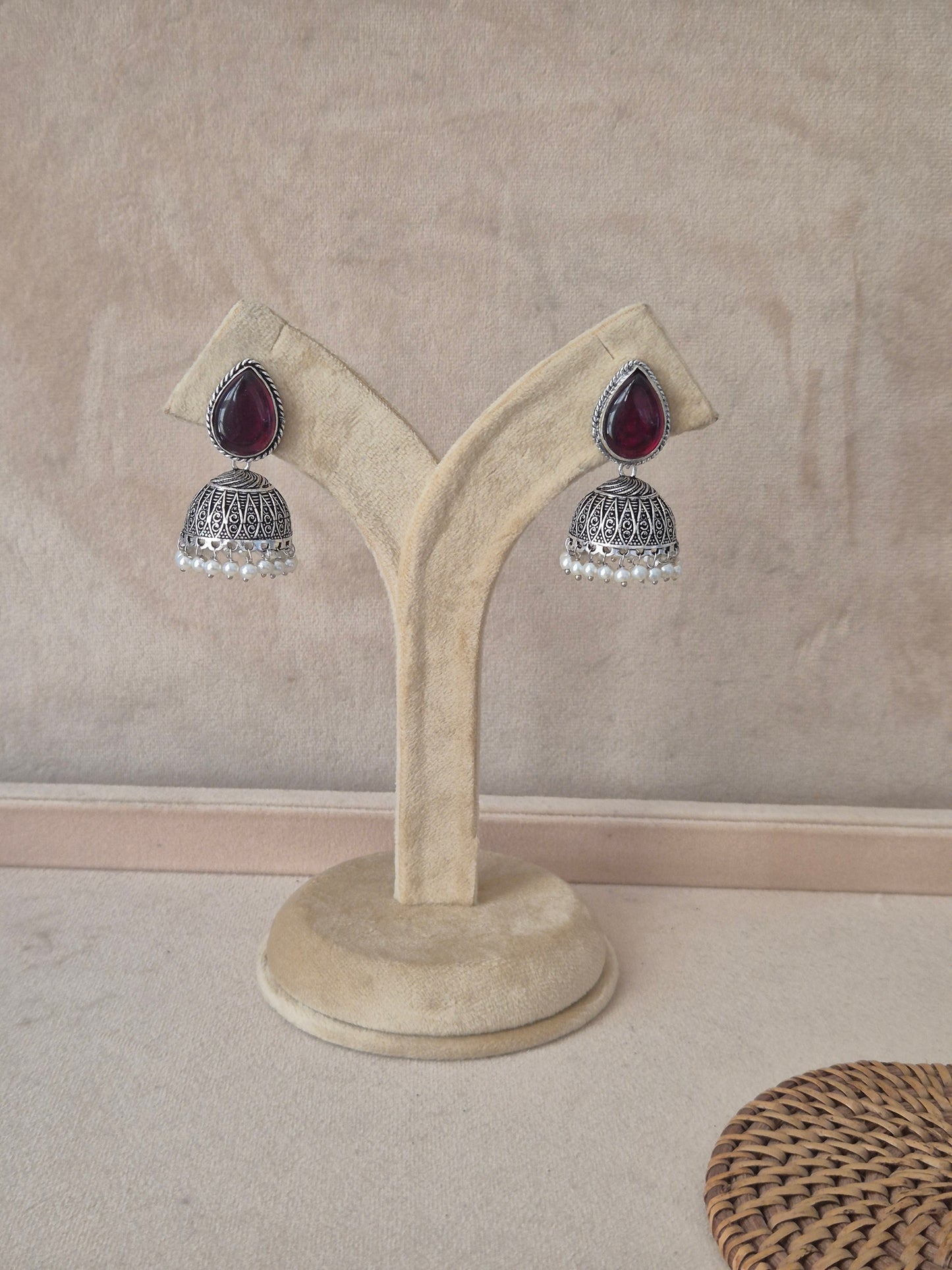 Pair of Kasturi silver-toned jhumka earrings featuring tear-drop shaped purple stones and pearl bead drops by naitri.in