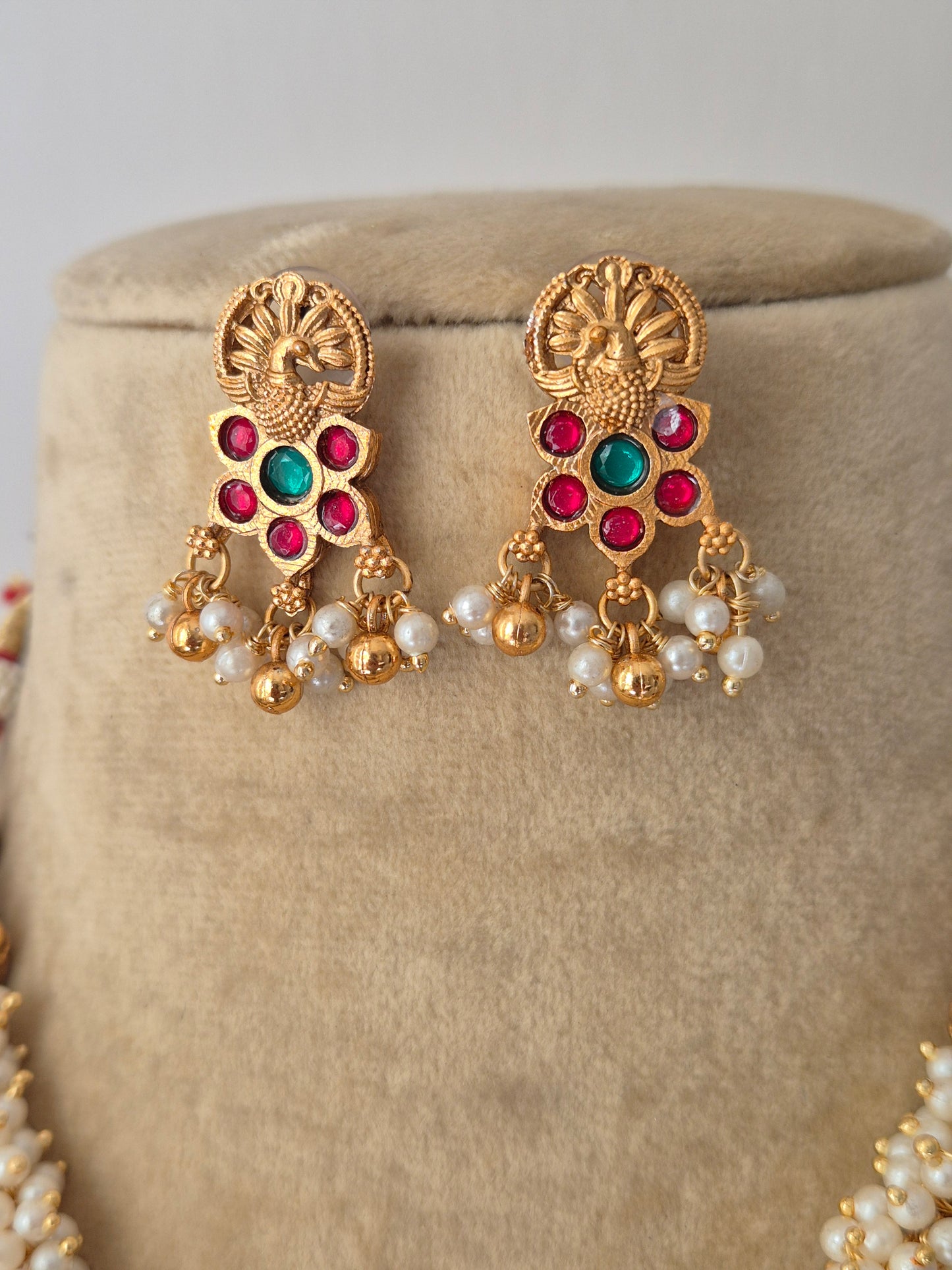 Traditional Indian gold-polished brass earrings, showcasing an intricate antique filigree earrings with ruby-red and emerald-green gemstones by naitri.in