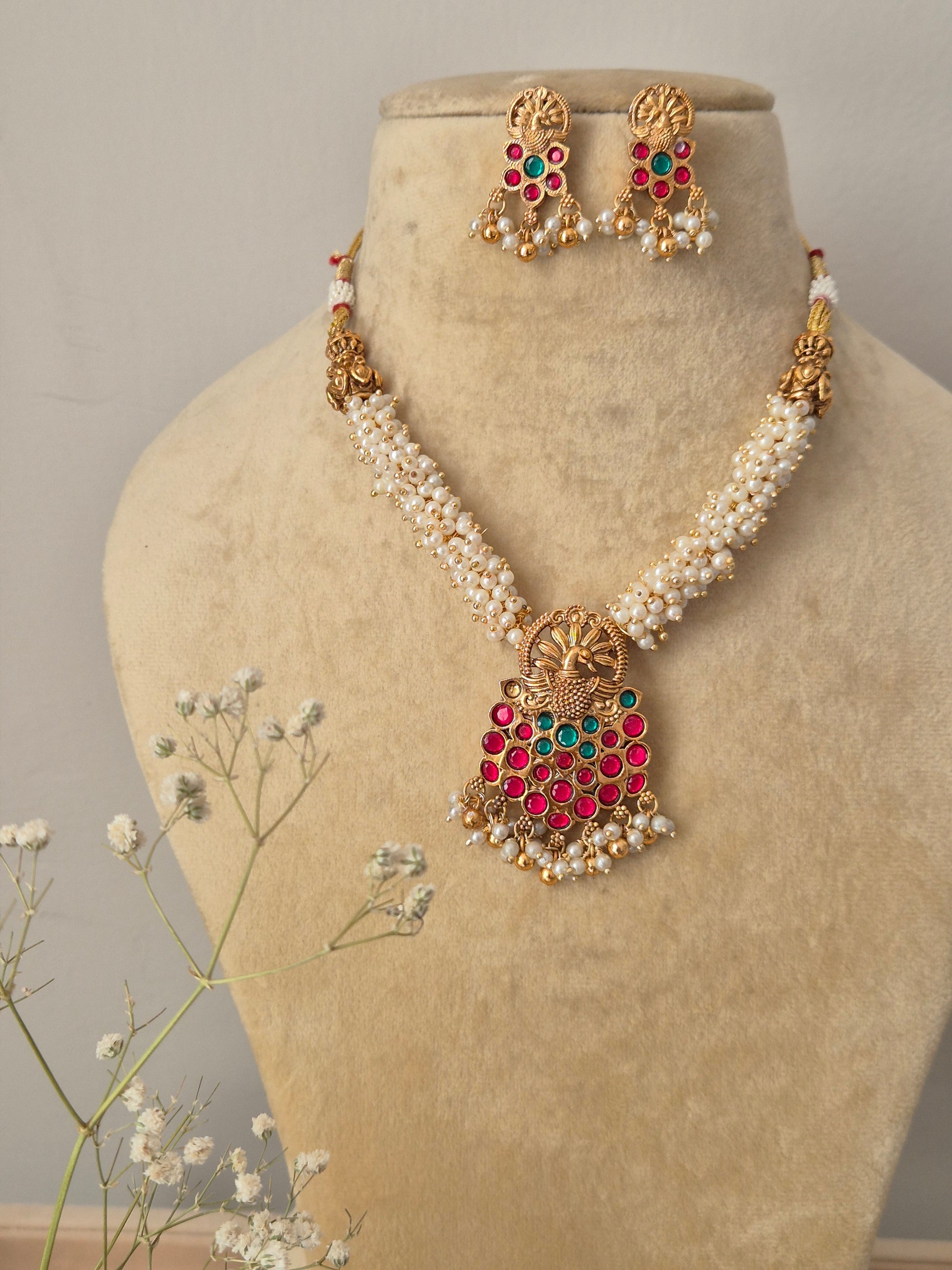 Kaveri Necklace Set: Gold-plated brass temple pendant with colorful stones and white pearl layers from the Naitri Golden Jewellery collection by naitri.in