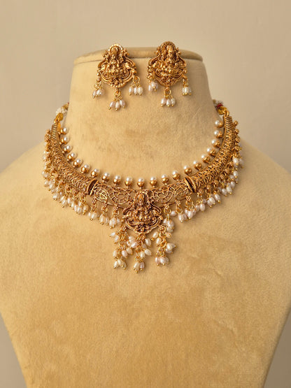 featuring a handcrafted golden temple jewellery choker with Goddess Lakshmi motifs, white pearl droplets, and matching jhumka-style earrings by naitri.in