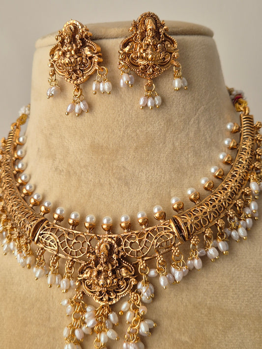 Handcrafted gold-plated temple necklace set with intricate deity carvings and delicate pearl accents by naitri.in