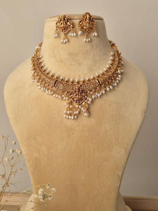 gold-toned chain holding a large temple-style pendant, paired with matching small drop earrings by naitri.in