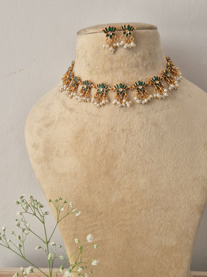Gold choker necklace with intricate green lotus-shaped accents and hanging pearl clusters, with matching earrings by naitri.in