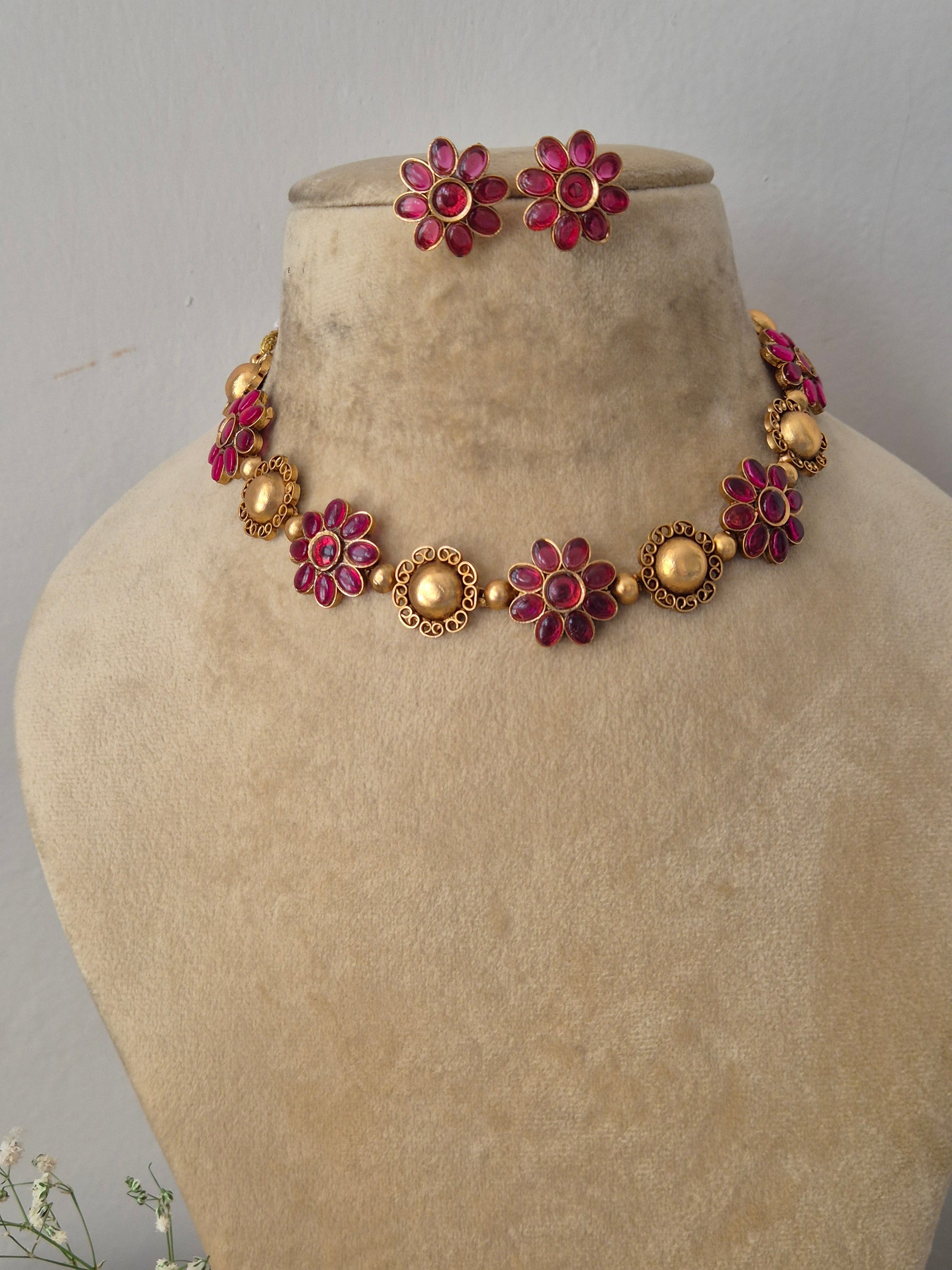 Elegant red gemstone and gold-toned traditional choker jewelry set, Gold-plated choker necklace with red floral gemstones and matching stud earrings by naitri.in 