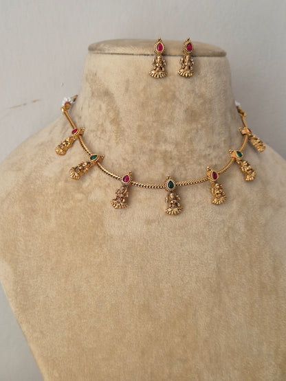Handcrafted antique gold statement jewelry set showcasing intricate traditional motifs and red-green gemstone embellishments, ideal for festive styling by naitri.in