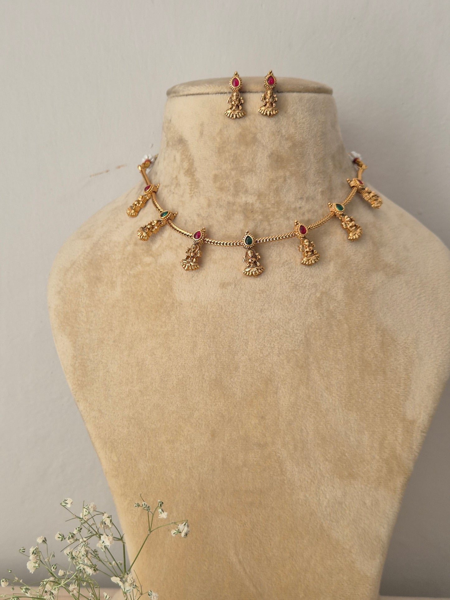 Gold choker necklace with green-red hanging deity charms and matching earrings by naitri.in