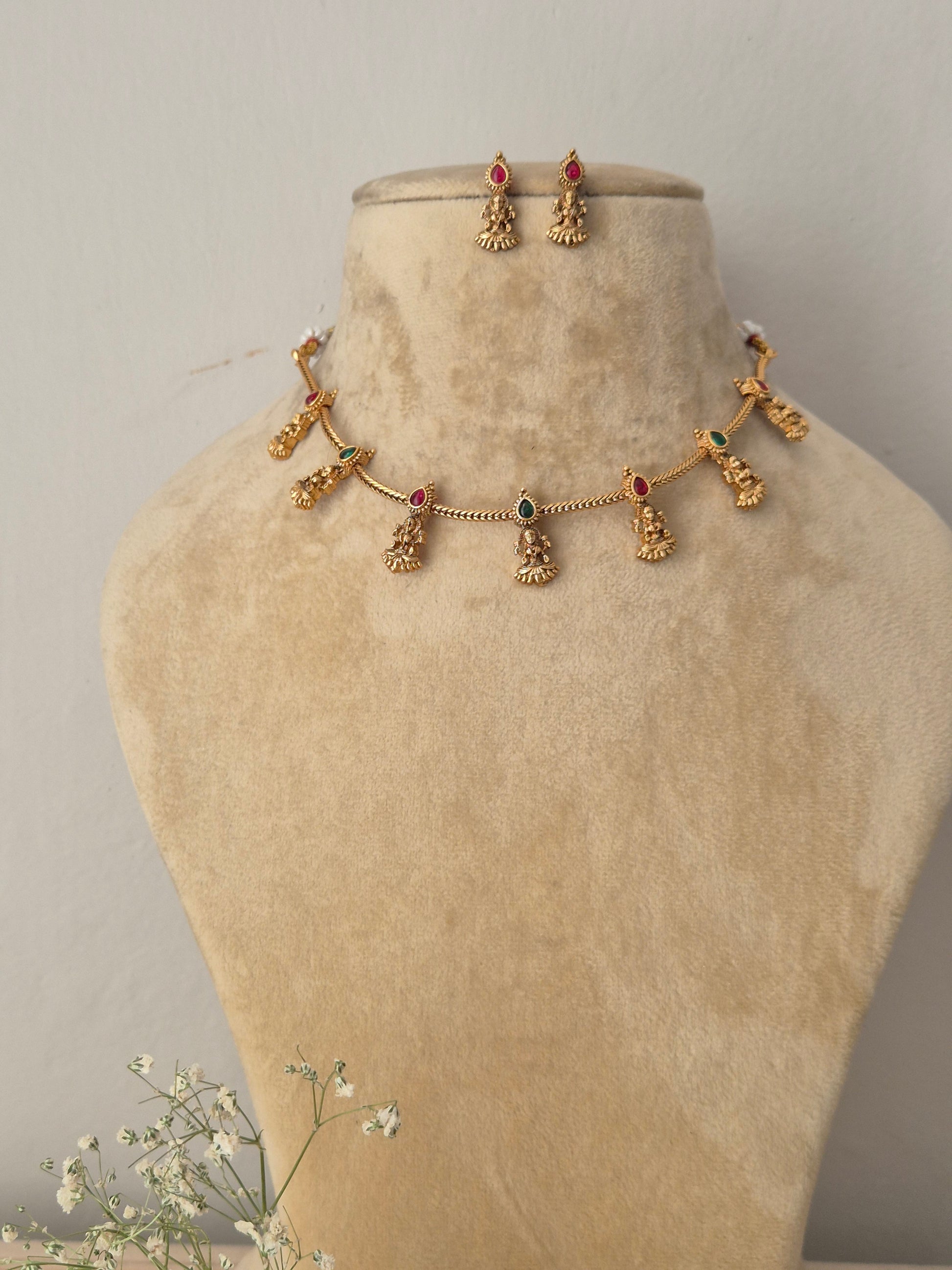 Gold choker necklace with green-red hanging deity charms and matching earrings by naitri.in
