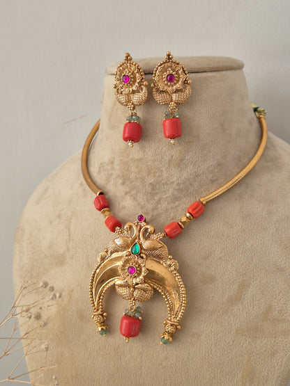 Traditional Indian gold-plated necklace paired with matching stud and coral drop earrings by Naitri.in