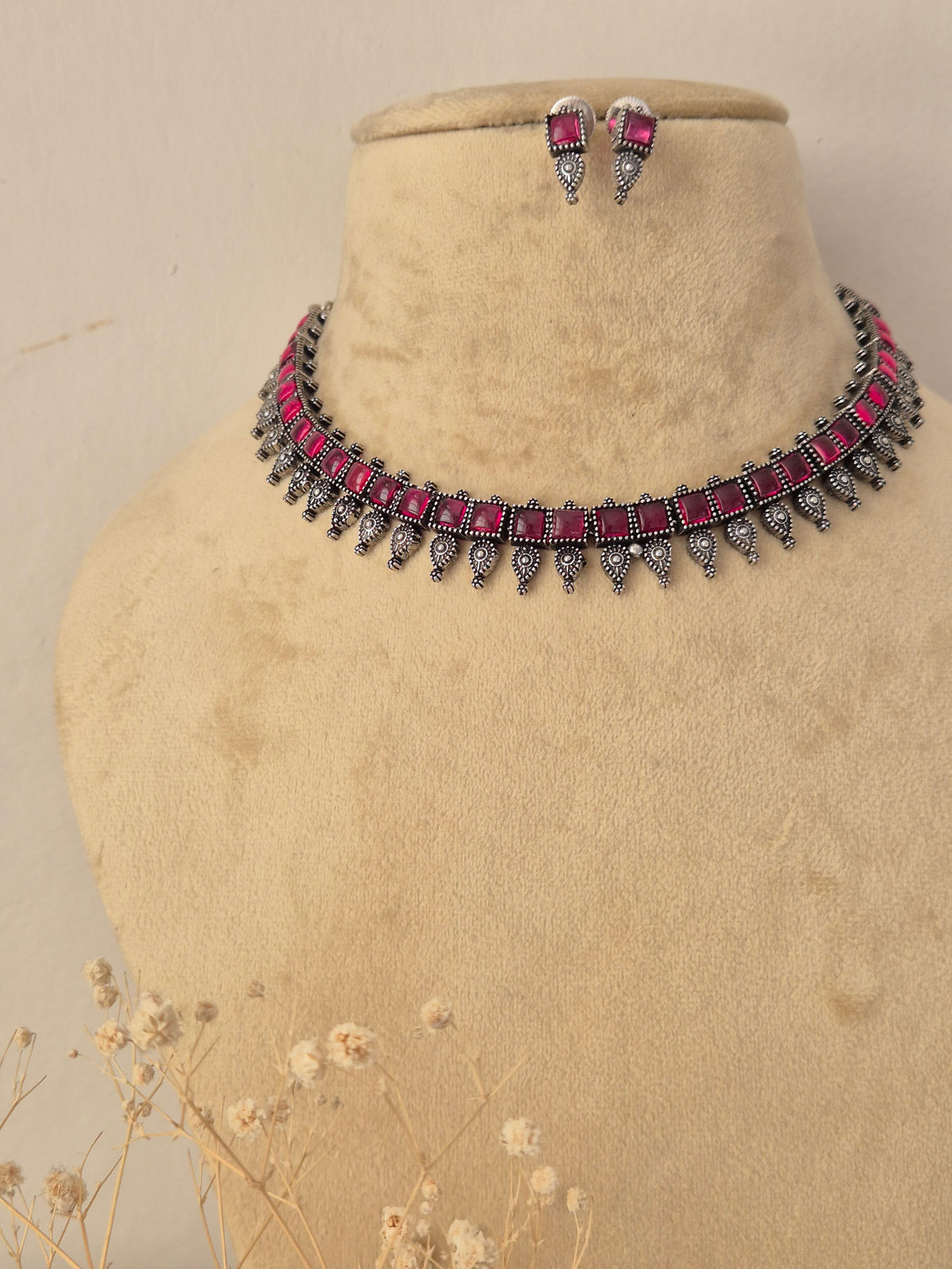 oxidized silver choker necklace featuring pink gem embellishments and dainty lower dangles, paired with matching pink stone earrings by naitri.in