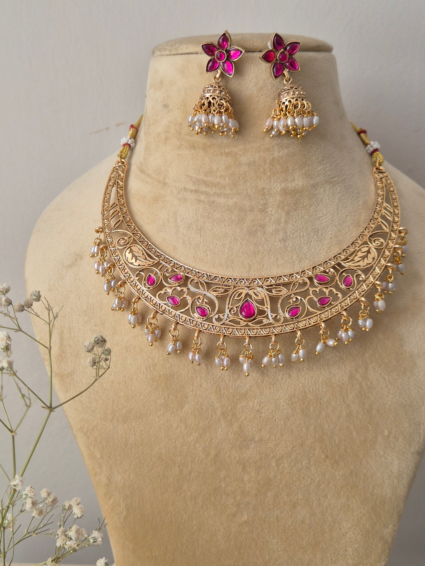 Komal Necklace Set: Gold-polished temple choker with pink stone accents, small dangling seed pearls, and coordinating festive jhumkas from the Naitri collection by naitri.in